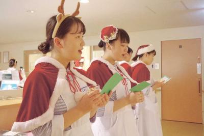 病棟の廊下でクリスマス曲を歌う学生
